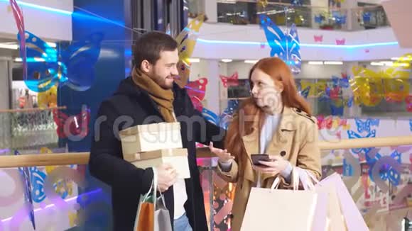 年轻的高加索夫妇在购物中心有智能手机视频的预览图