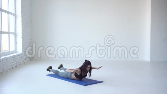健康的健身女性正在伸展背部她正在白色工作室的练习垫上做背部扩展4k视频的预览图