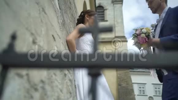 穿着蓝色西装结婚花束的英俊时髦新郎正带着漂亮的新娘来到他迷人的新娘身边视频的预览图