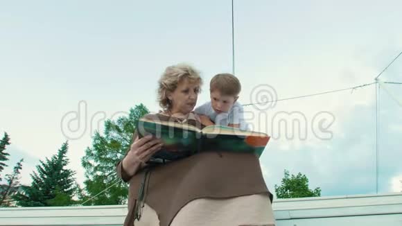 奶奶和孙子在公园夏天读一本书视频的预览图