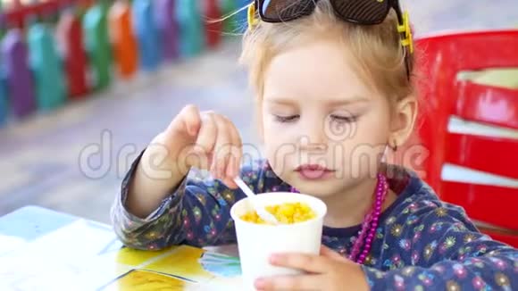 小女孩在夏季公园吃街头美食玉米旅游美食概念视频的预览图