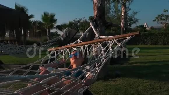 穿泳衣的女孩躺在吊床上视频的预览图