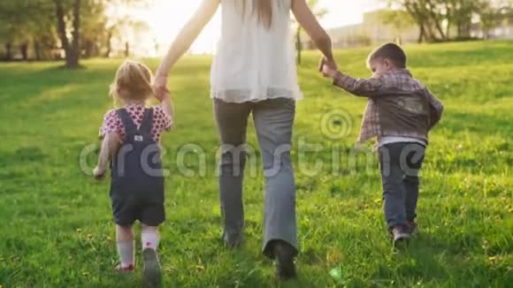 在日落时分妈妈和孩子们手拉手一起在草地上奔跑视频的预览图