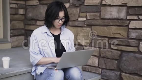 戴眼镜的亚洲女人在外面用笔记本电脑工作视频的预览图