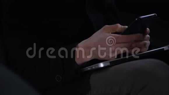 年轻迷人的男性手持和滚动智能手机而坐骑在车里视频的预览图