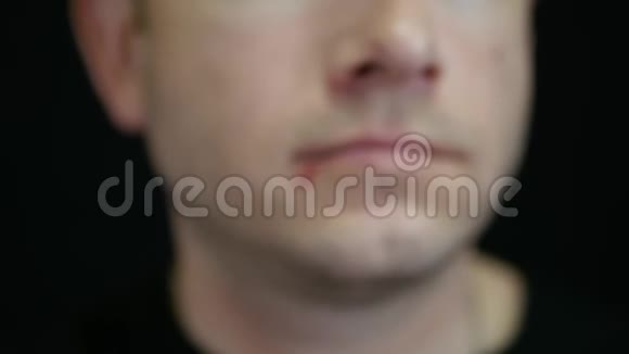 一个男人在黑色背景下摸着嘴唇上的溃疡疱疹视频的预览图