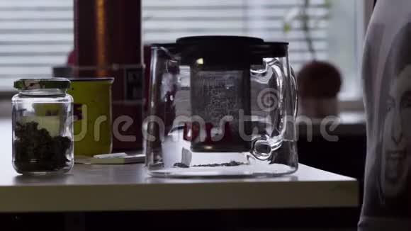 男人在桌子上用大杯子和玻璃茶壶做卷烟视频的预览图