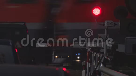 在一列过往列车的背景下夜间在一个铁路十字路口闪烁红色交通灯视频的预览图