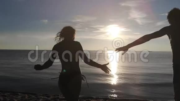 一对年轻幸福的夫妇在海滩上手牵着手挥着手飞向大海视频的预览图