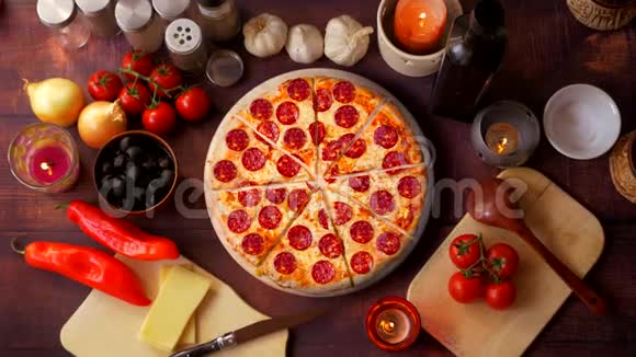 把意大利辣香肠披萨和蔬菜和蜡烛旋转在桌子上视频的预览图