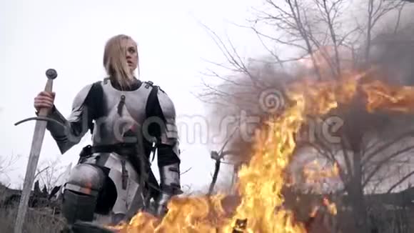 穿着盔甲的圣女贞德坐在火旁环顾四周动作缓慢视频的预览图