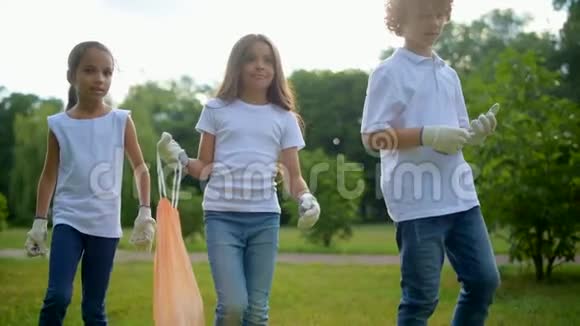 快乐的小志愿者拿着垃圾袋在公园里走来走去视频的预览图