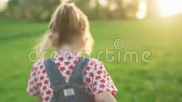 阳光明媚的夏日小女孩在公园的草坪上嬉戏视频的预览图