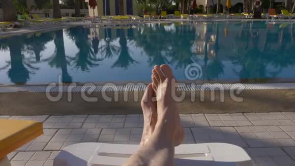 男性的脚躺在躺椅前游泳池的豪华场所视频的预览图