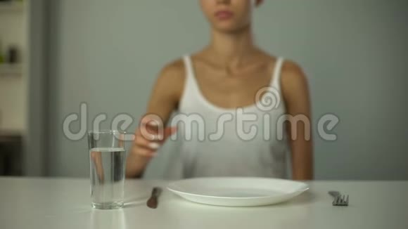 厌食女孩坐在空盘子前喝水严重饮食视频的预览图