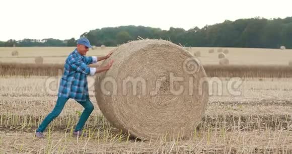 微笑的农夫在农场里翻滚干草打手势视频的预览图