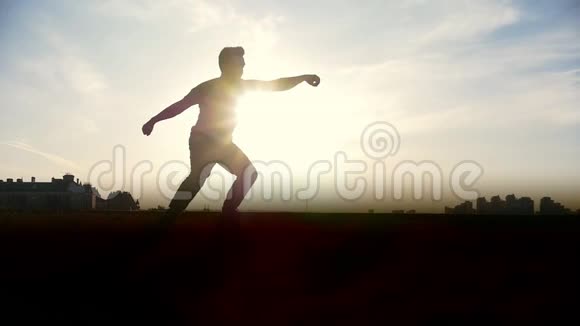 慢动作年轻的雄性跑酷特技跳投者在太阳面前表演惊人的翻转动作视频的预览图