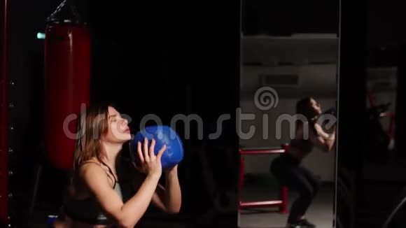 那个女孩用手里的球表演蹲有氧训练视频的预览图