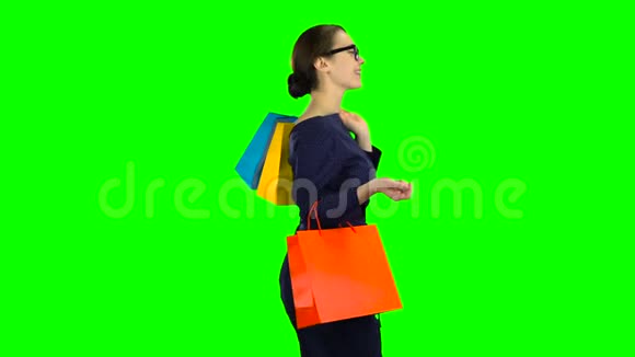 手里拿着购物包的女孩正沿着街走绿色屏幕侧视图视频的预览图