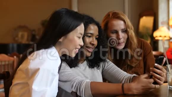 多民族女孩在咖啡厅玩智能手机技术视频的预览图