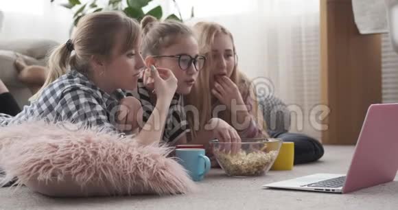 女孩吃爆米花看笔记本电脑上的媒体内容视频的预览图