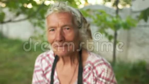 一位在花园里工作的80岁高龄妇女的动态肖像紧皱的双手将干草加入到一个视频的预览图