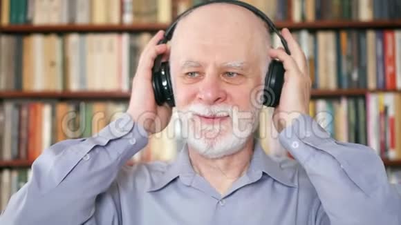 开朗的老人用无线耳机听音乐退休的梅洛曼跳舞视频的预览图