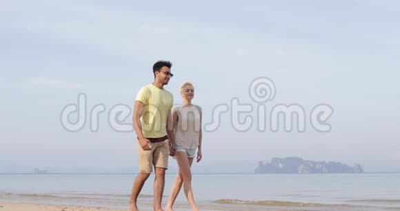 情侣在沙滩上牵手交谈青年男女欢笑游客度假视频的预览图