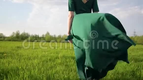年轻漂亮的女人穿着漂亮的裙子站在夕阳下的田野里视频的预览图