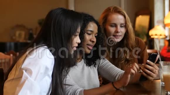 多民族女孩在咖啡厅玩智能手机技术视频的预览图
