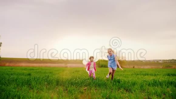 两个无忧无虑的带着气球的小女孩在日落的时候在绿茵场上奔跑吧快乐的童年梦想视频的预览图