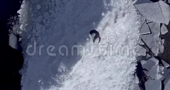 鸟瞰年轻活跃的快乐男子停留在冰冰冰川附近的冬季海洋海岸线无人视野视频的预览图