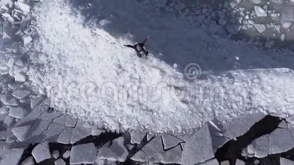 鸟瞰年轻活跃的快乐男子停留在冰冰冰川附近的冬季海洋海岸线顶部视图视频的预览图
