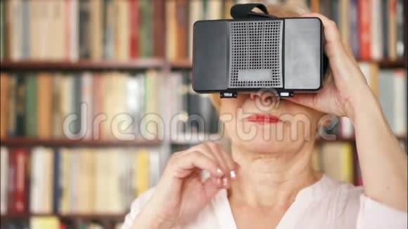 老年女性在家使用VR360眼镜活跃的现代老年人背景书架视频的预览图
