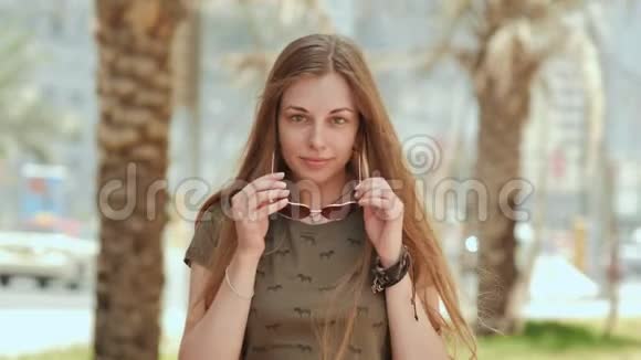 戴太阳镜的女孩在迪拜的街道和棕榈树的背景上视频的预览图