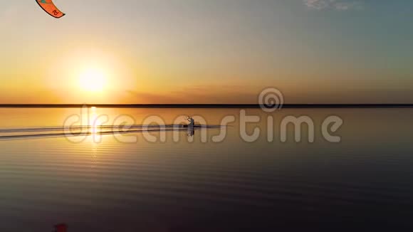夕阳西下的湖面上男人控制着一只明亮的训练风筝视频的预览图