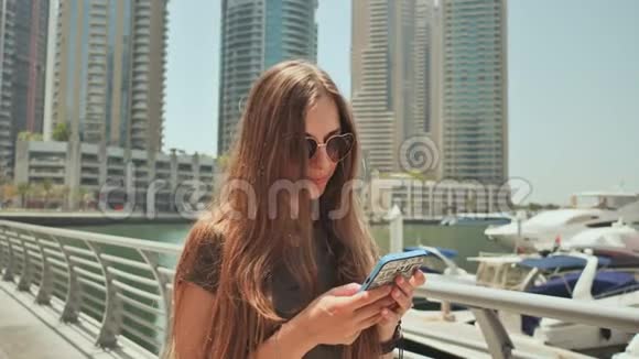 一个长发女孩在迪拜码头的智能手机上拨了一条信息视频的预览图