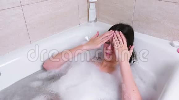 漂亮的黑发女人在家里的浴室里脸上涂了一层擦洗面的特写视频的预览图