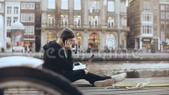 4K白种人商人外面有笔记本电脑坐在街上的人在打电话阿姆斯特丹企业家视频的预览图