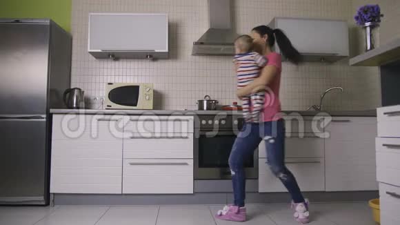 漂亮的妈妈和快乐的宝宝在厨房跳舞视频的预览图