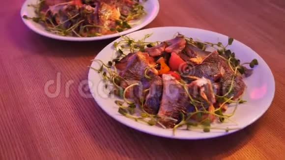 精致的鱼盘两盘鱼和蔬菜用生菜叶装饰特写镜头移动视频的预览图
