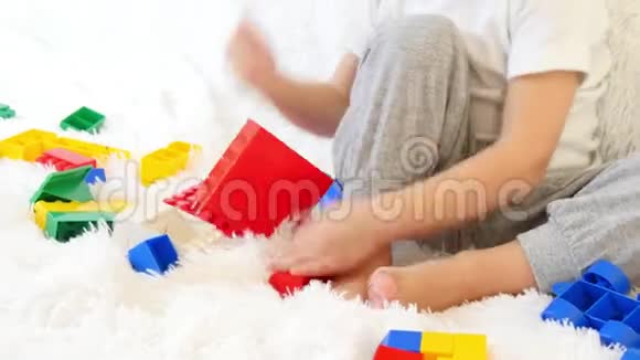小男孩玩彩色积木坐在沙发上的白色背景特写运动相机滑块视频的预览图
