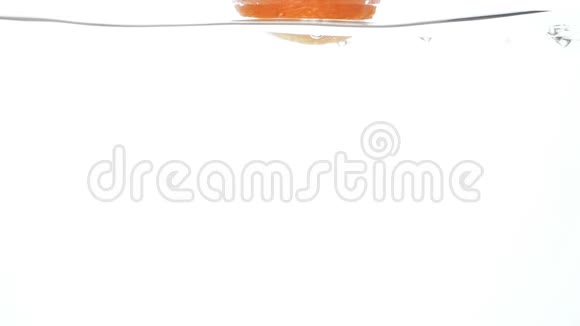 橙色在白色背景下在清澈的冷水中缓慢下落和飞溅的特写视频视频的预览图