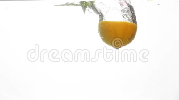 特写慢镜头多汁和成熟的柑橘类水果掉进水里橙子和柠檬的半瓣和薄荷视频的预览图