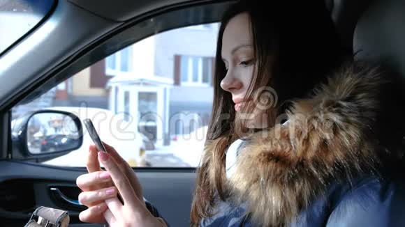 有手机的女人在车里年轻漂亮的黑发女人在看手机里的东西然后转向视频的预览图