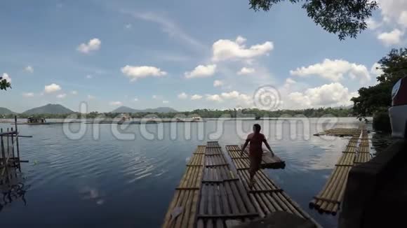 男子从竹筏上下来竹竿旁用来养鱼笼视频的预览图