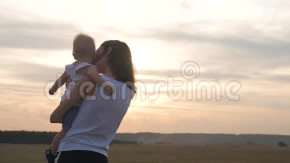 快乐的母亲在日落时和小儿子玩年轻的白种人妈妈和小男孩晚上在户外玩得很开心视频的预览图
