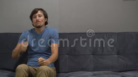 一个年轻人坐在沙发上感到压力和愤怒右侧复制空间视频的预览图