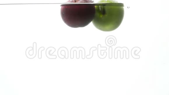 两个鲜红色和绿色的苹果在白色背景下在冷水中落下和溅起慢动作视频视频的预览图