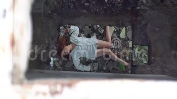 俯视着躺在废弃精神病院废墟上的穿着白色衬衫的病妇病人视频的预览图